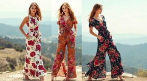 Página Inicial 5 Três mulheres loiras posando em paisagem montanhosa usando macacões estampados florais em diferentes estilos: modelo da esquerda veste macacão longo sem mangas com estampa de rosas vermelhas sobre fundo bege claro, modelo do centro usa macacão com manga curta e decote em V na cor terracota com flores rosas e folhagens, modelo da direita veste macacão transpassado de manga curta na cor azul marinho com estampa floral colorida, todas as peças possuem amarração na cintura e as modelos estão descalças sobre terreno rochoso com vista panorâmica de montanhas ao fundo sob luz natural dourada